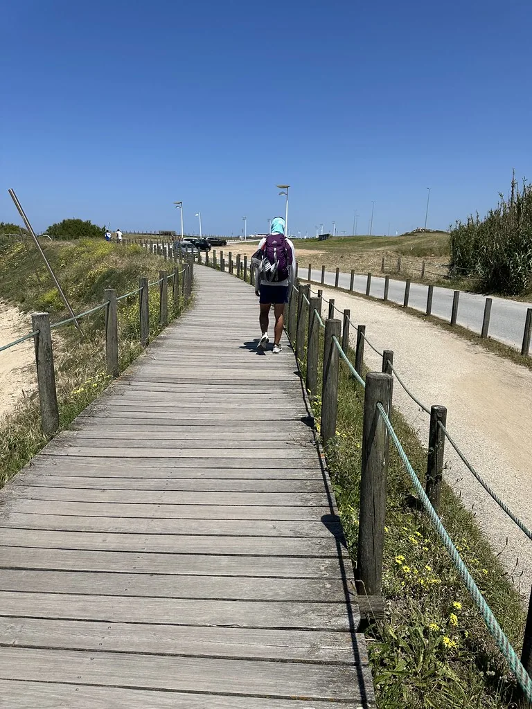Peregrino caminando por una pasarela de madera junto a la costa portuguesa