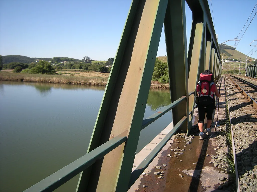 A pilgrim crossing a metal bridge on the Camino del Norte